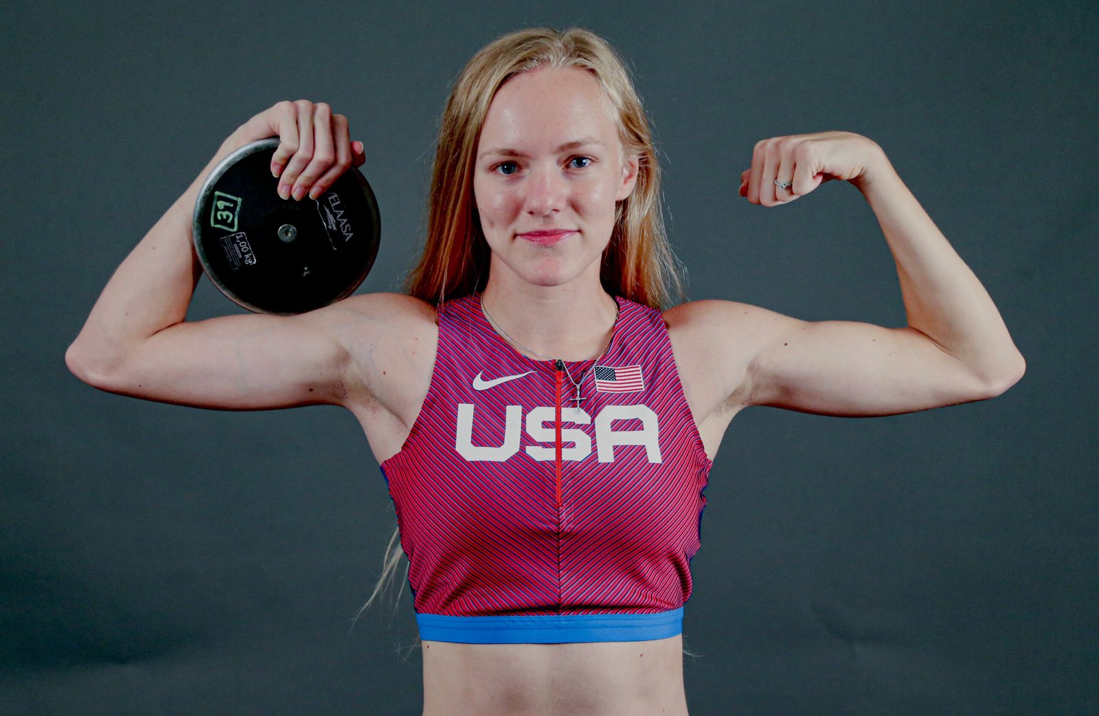 Jessica is smiling and flexing while holding the discus.