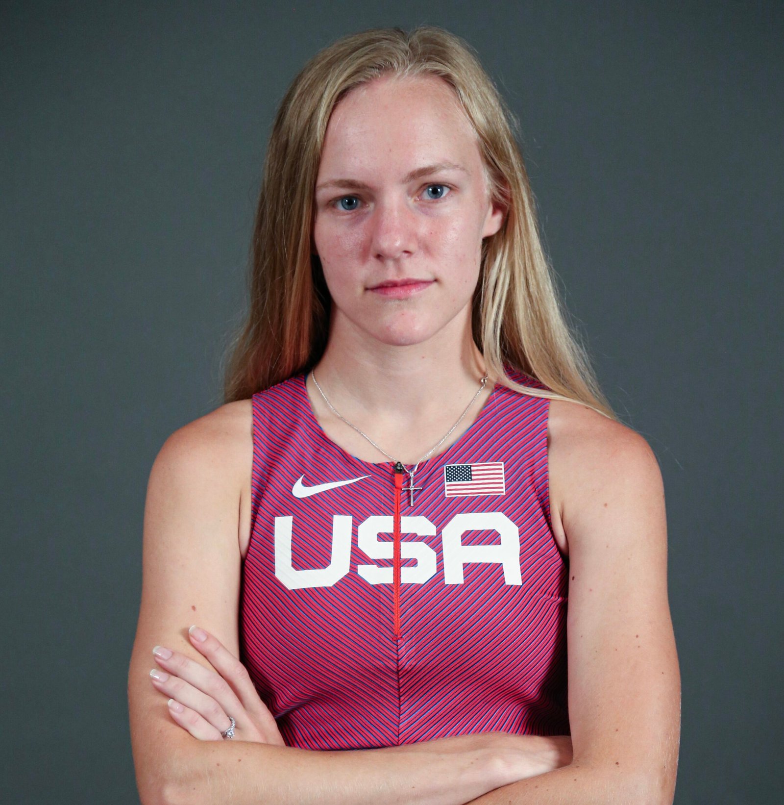 Jessica Heims, a white and blonde woman is looking at the camera, wearing a red USA track shirt.